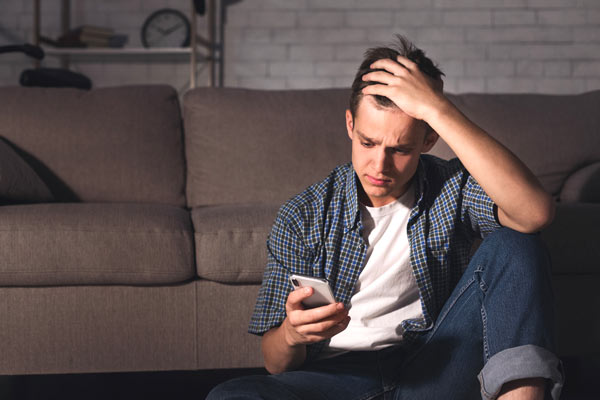 Young man reading bad news on his phone