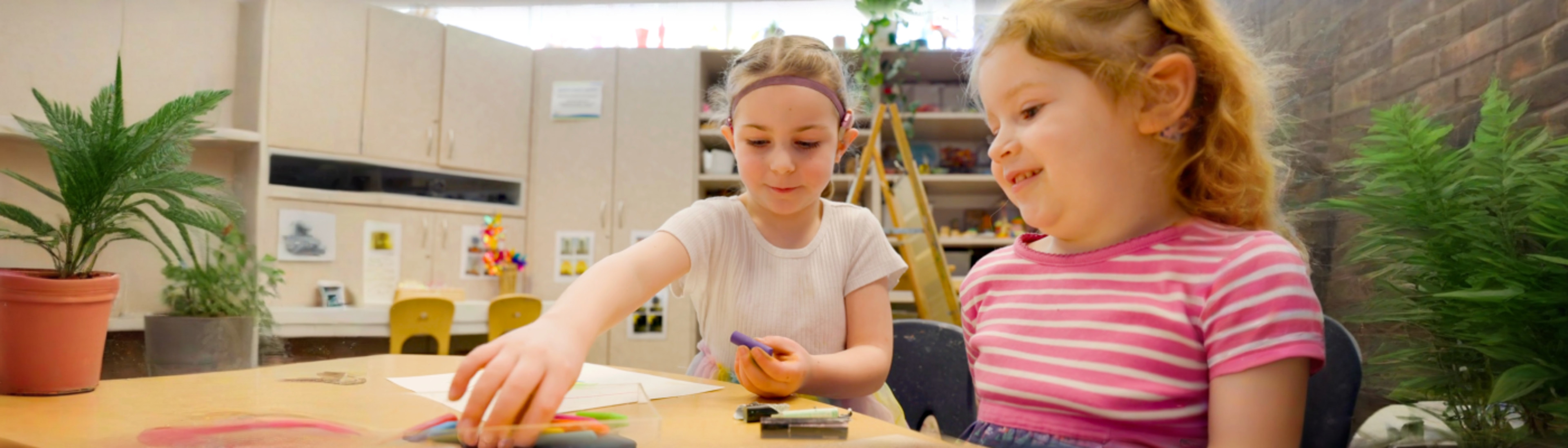 two kids with hearing aids coloring