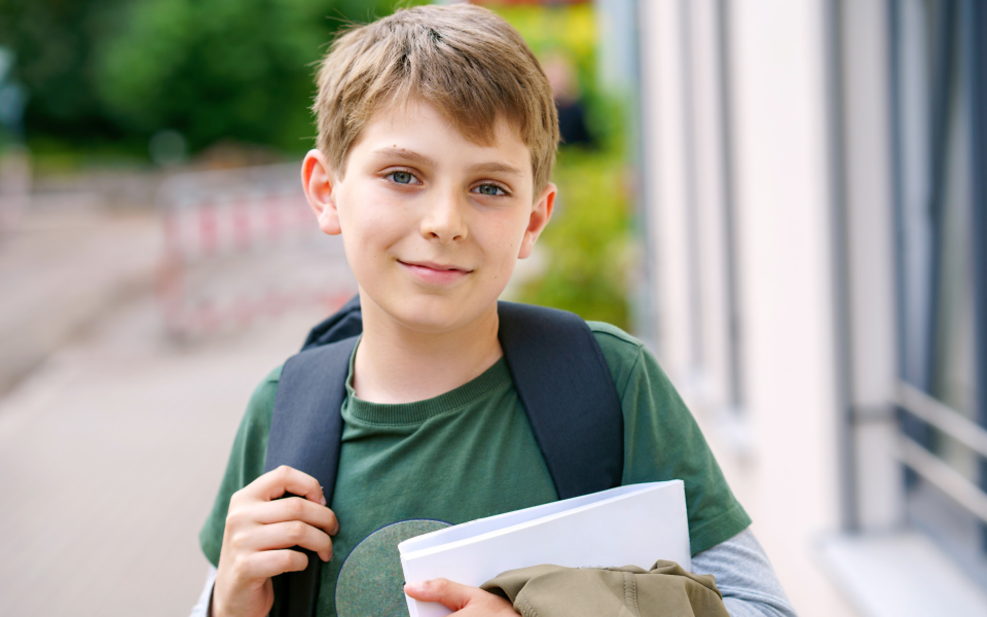 Boy holding school work with backpack