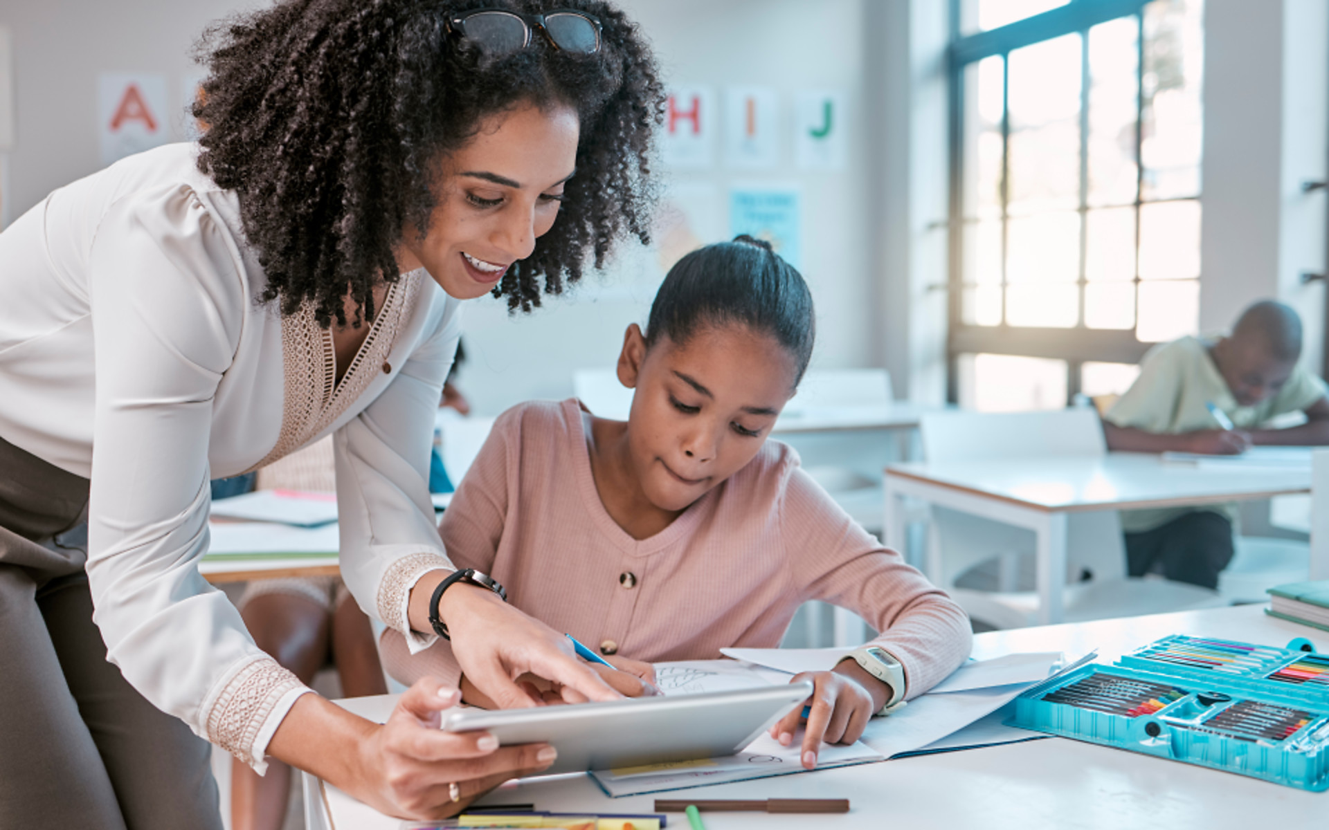 Female teacher helping young girl in class