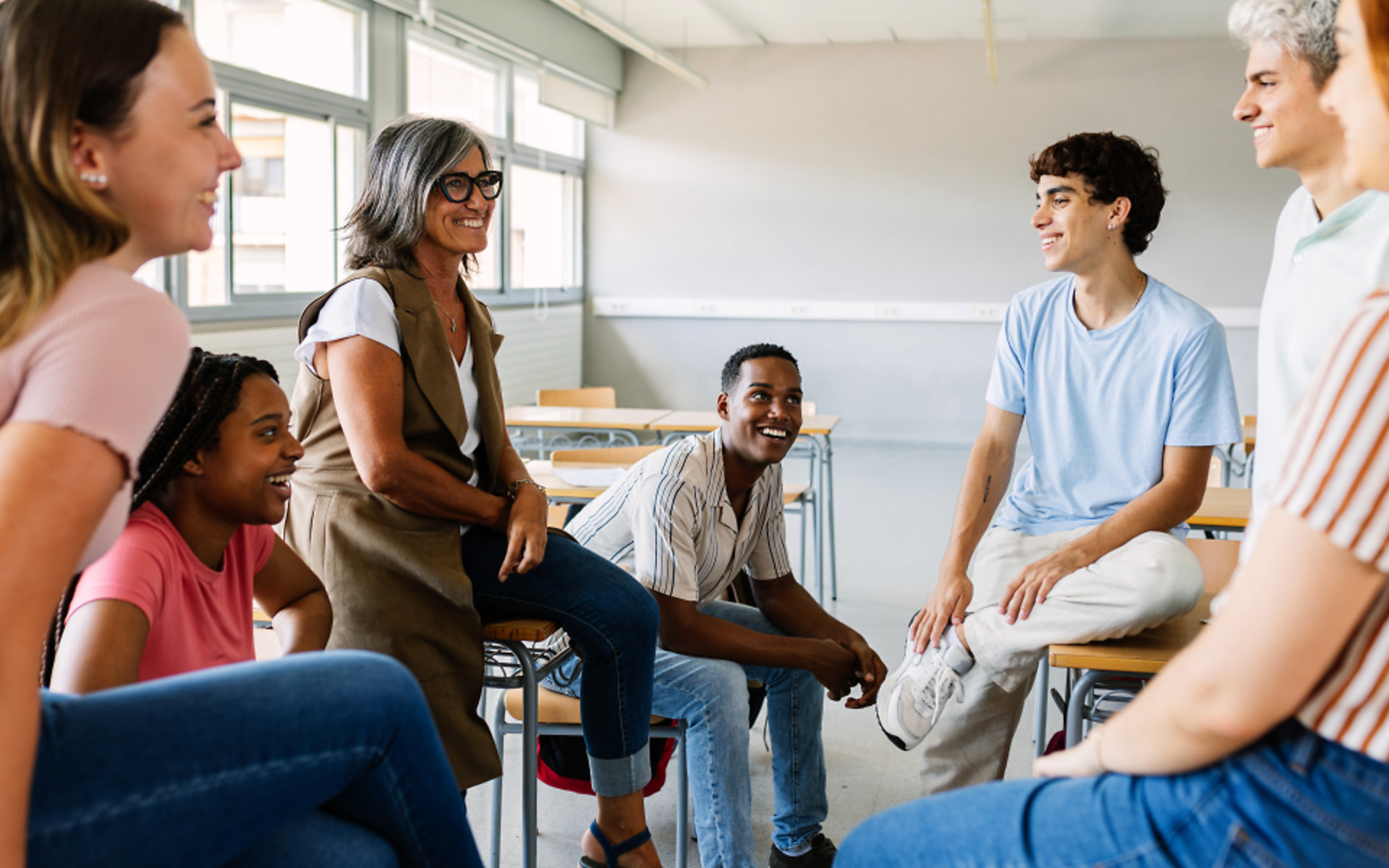 High school students talking with teacher in classroom
