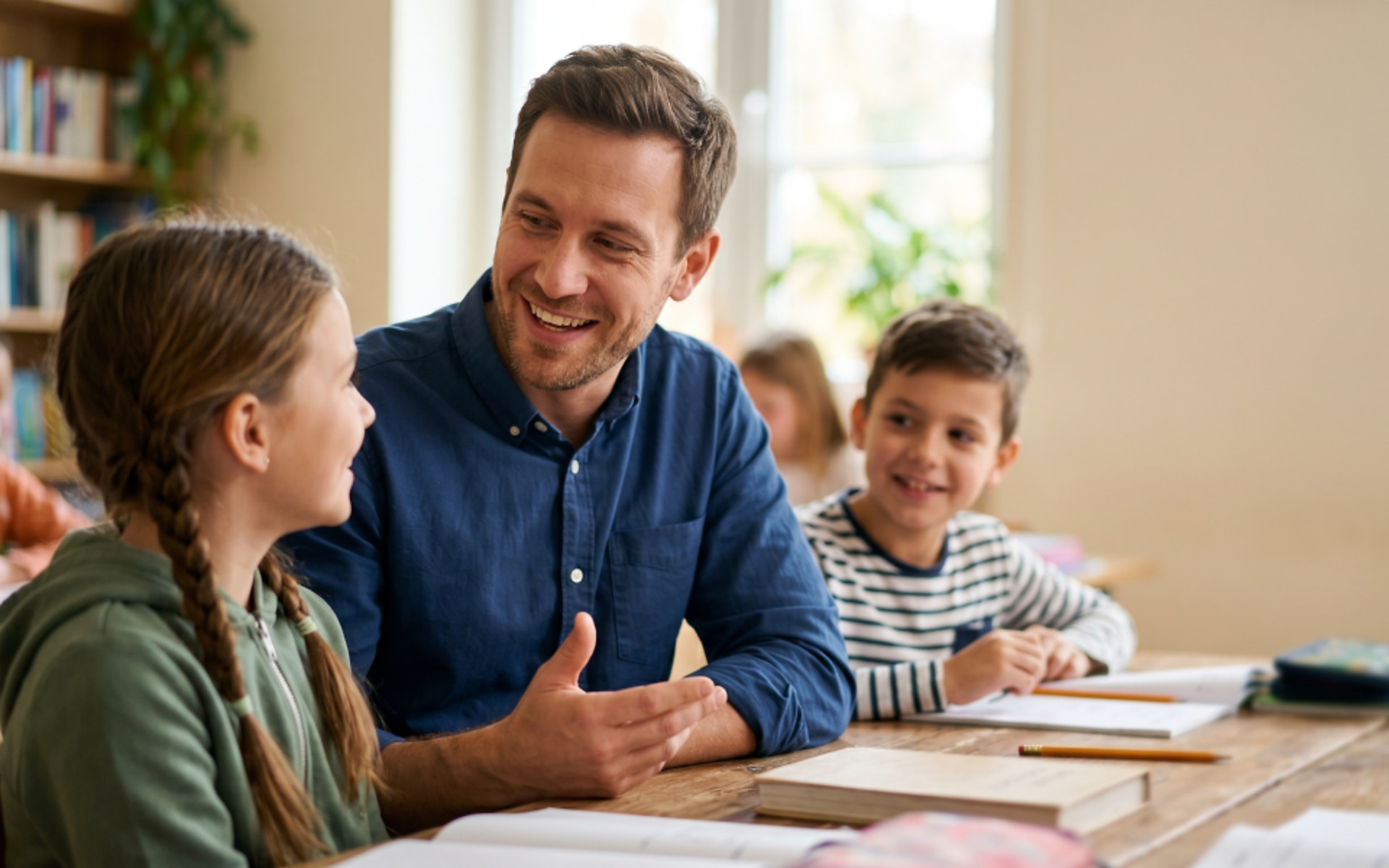 Teacher talking with schoolgirl in classroom during group study session